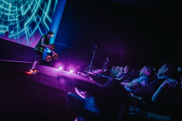 Freestyle footballer performing on stage under purple light